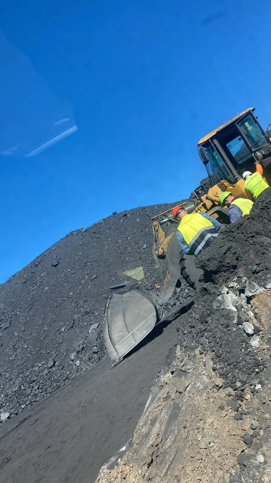 Loader and mine crew at work beside a mining stockpile